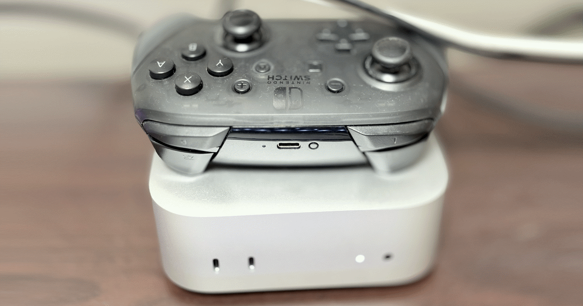 照片：桌上的銀色 Mac mini，上面擱著一個 Switch Pro 手把
